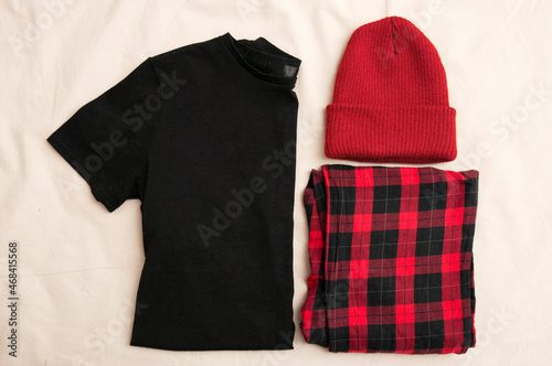 A set of clothes consisting of a black T-shirt, plaid pajama pants and a hat. Lazy days. Everyday clothes for the weekend.
