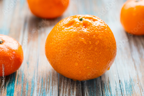 Juicy ripe tangerine with water droplets on a wooden background.