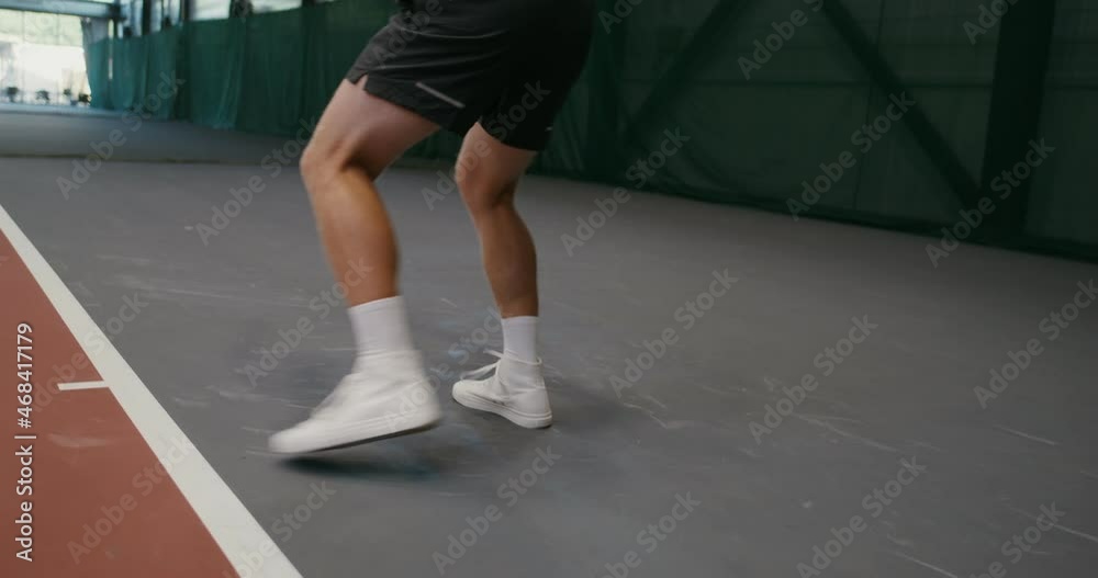 A man plays tennis, hitting ball by ball with a racket, playing indoor A man plays tennis, hitting ball by ball with a racket, playing indoor