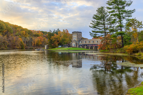 Beautiful lakeside view of Fall foliage and an old building in a park in the morning.
