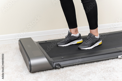 Sporty woman using walking treadmill in the interior of the room or home.