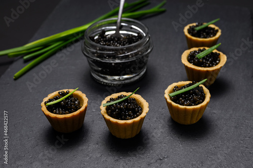 delicacy - close-up of black sturgeon caviar in tartlets. Studio shot on slate background