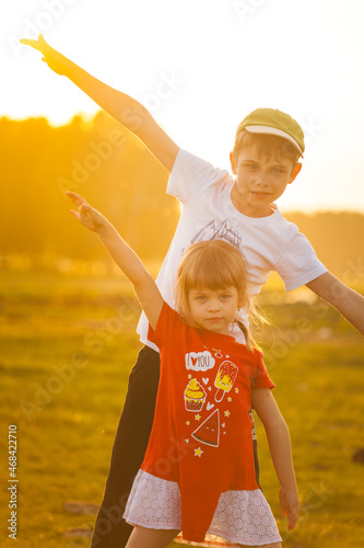  Children play an airplane and laugh against the backdrop of the setting sun © Yan Gordiza