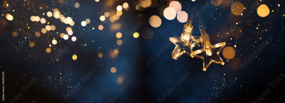 Leinwandbild Motiv - tomertu : Christmas warm gold garland lights over dark background with glitter overlay