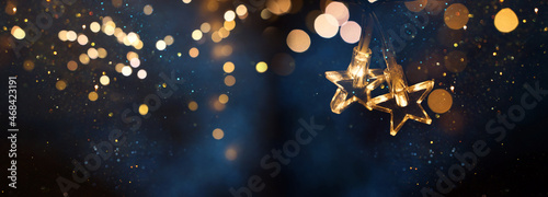 Christmas warm gold garland lights over dark background with glitter overlay