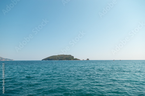 An island in the open sea on the horizon, land among the water. © Plutmaverick