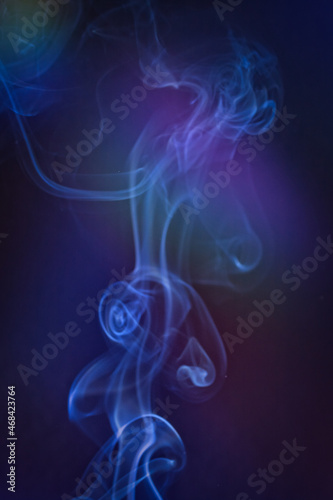 A vertical shot of smoke in colorfull backlight with a blue note
