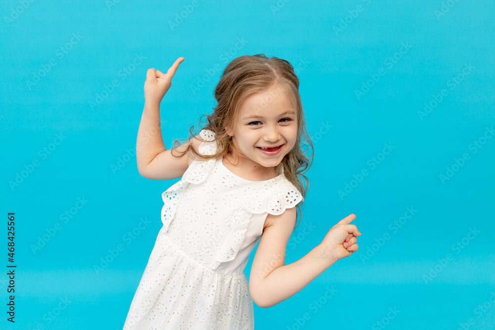 Happy cute little girl in a cotton white dress on a blue background in ...