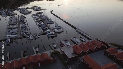 Aerial view of a boat arriving at a small marina outside Gothenburg on a beautiful summer evening at sunset. 4K drone footage.