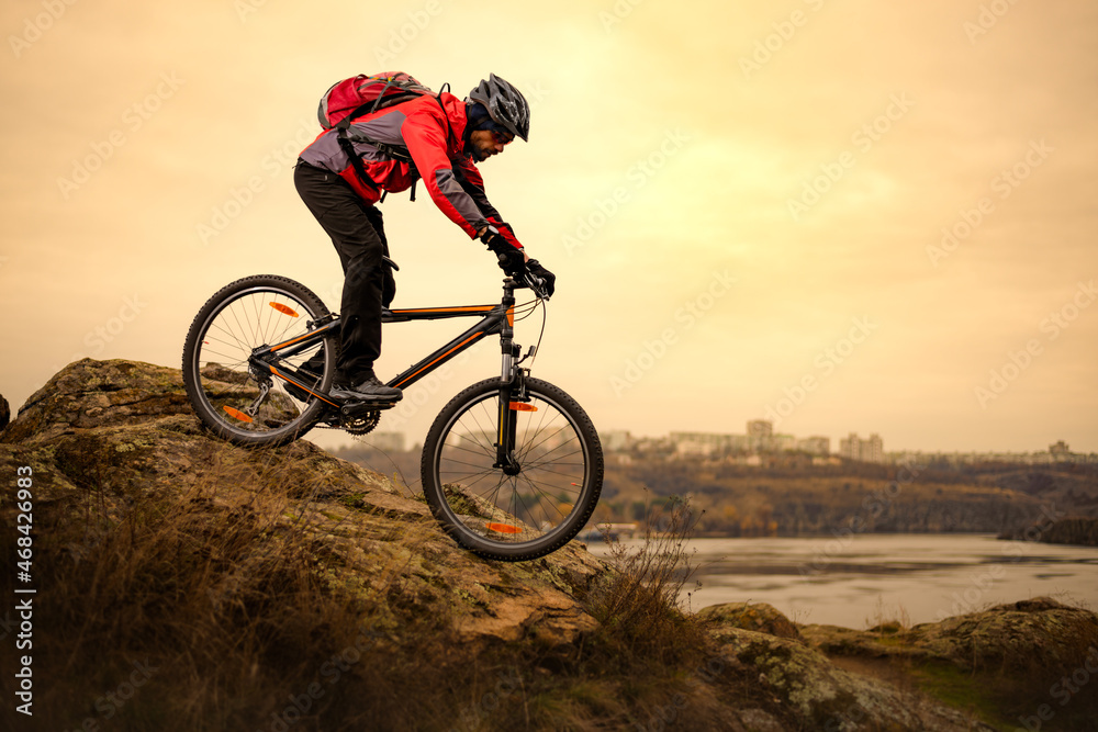 Cyclist Riding the Mountain Bike on the Rocky Trail at Cold Autumn Evening. Extreme Sport and Enduro Cycling Concept.