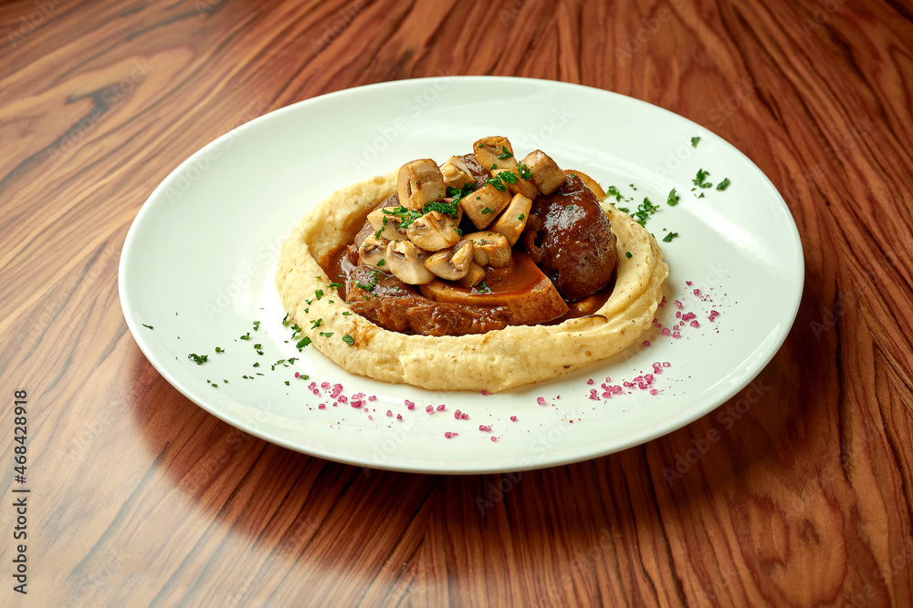 Ossobuco steak with mushroom sauce and mashed potatoes on a wooden table
