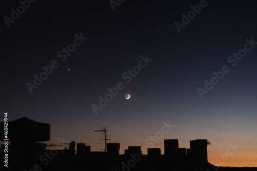 waxing crescent moon over city