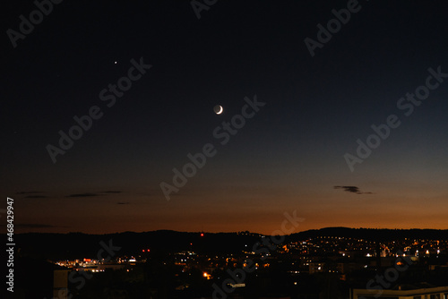 waxing crescent moon over city