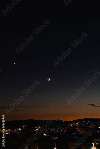 waxing crescent moon over city