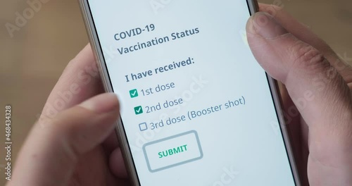 Concept of Covid-19 vaccinated status with hands ticking first, second and third (booster shot) dose on phone screen, after vaccination. POV, close up, coronavirus, form, app. photo