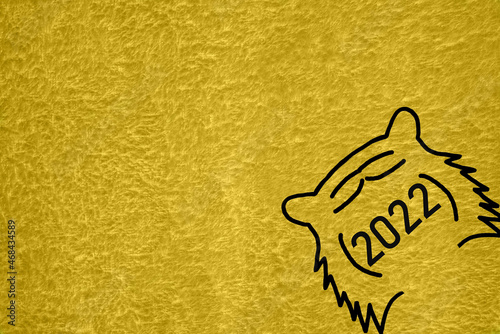 On a yellow (mustard) pile background there is a black outline of a tiger's muzzle and the numbers 2022.