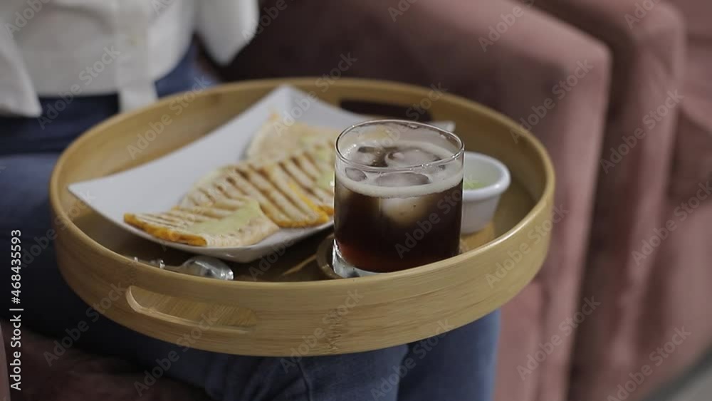 chica sentada en salon de belleza tomando un tea helado en una bandeja de madera
