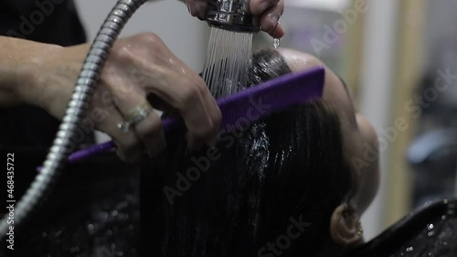 En un salón de belleza, una peluquería peinando el pelo mojado del cliente con masaje, camara lenta photo