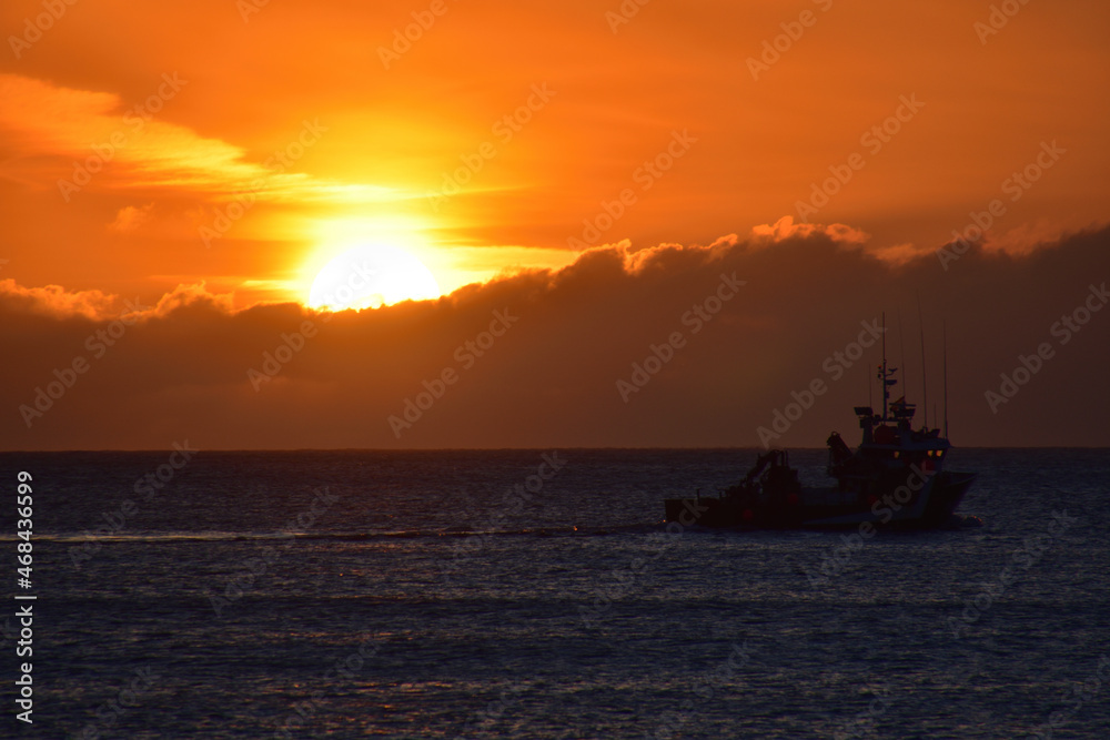 Sunset on the sea with a boat passing by on the beach of Doniños in Ferrol