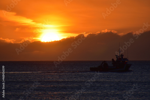 Sunset on the sea with a boat passing by on the beach of Doniños in Ferrol