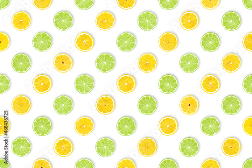 Lemon meets lime: healthy fruits background. Pattern of freshly cut lemon and lime slices against white background. Table top view, flat lay.
