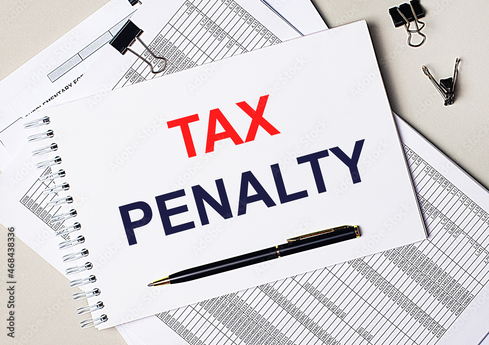 On the desktop there are documents, pen, black paper clips and a notebook with the text TAX PENALTY. Business concept On the desktop there are documents, pen, black paper clips and a notebook with the text TAX PENALTY. Business concept