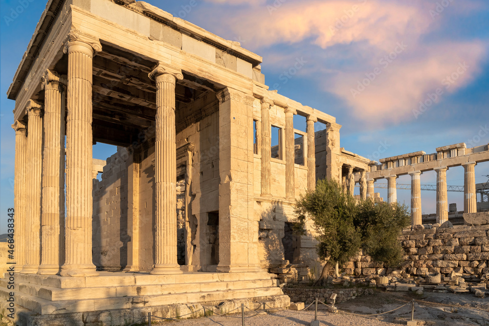 Erechtheion Temple (Erechtheum) with the Caryatids at the archaeological site of Acropolis in Athens, Greece. Parthenon Temple in the background. Angled front view, colorful clouds, blue sky
