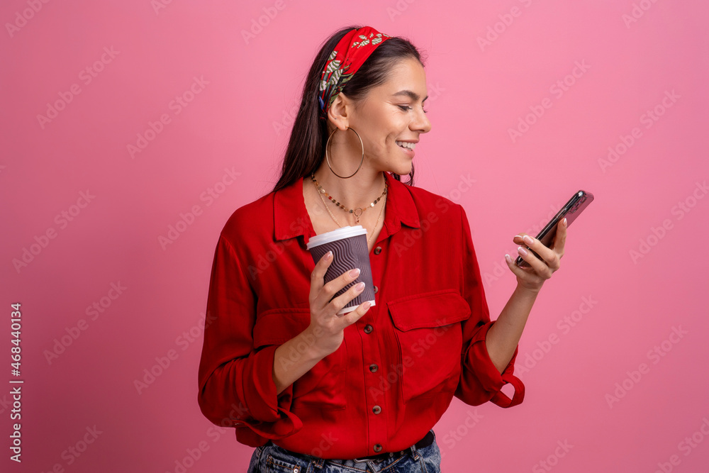 Naklejka premium hispanic beautiful woman in red shirt smiling holding smartphone
