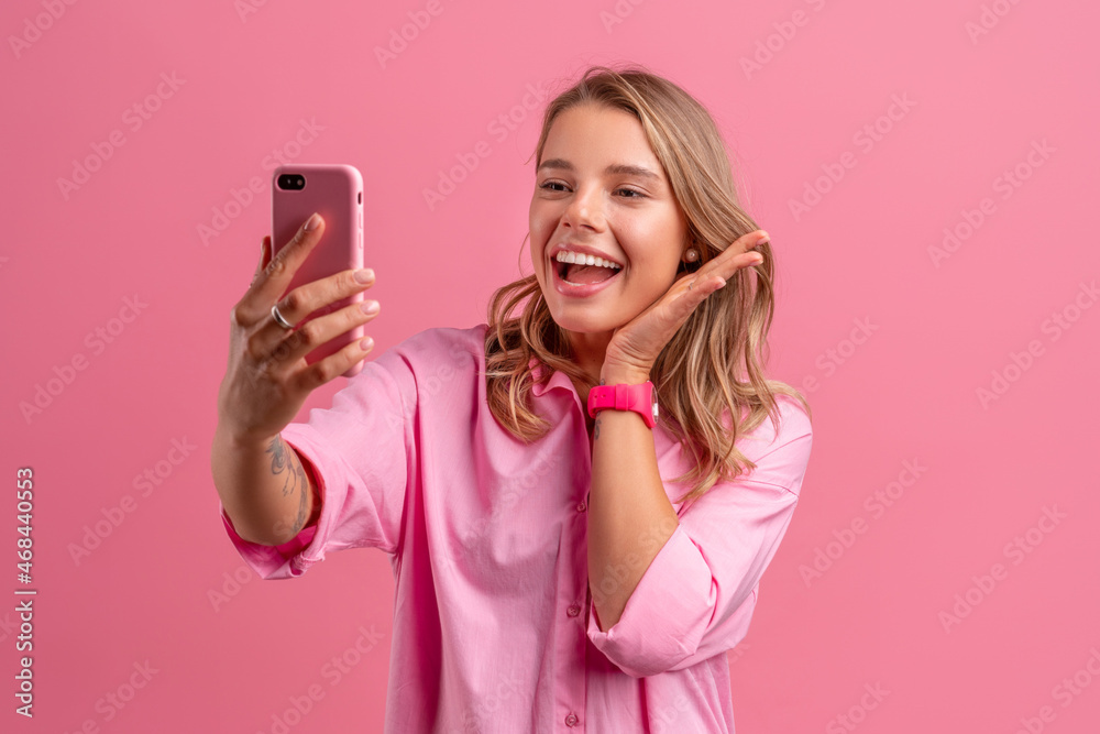 blond pretty woman in pink shirt smiling holding holding using smartphone blond pretty woman in pink shirt smiling holding holding using smartphone