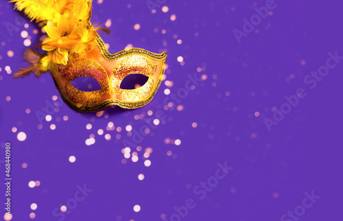 Golden Carnival mask on purple background with sparkles. Blurred effect. Mardi Gras concept. Copy space © Nataliia