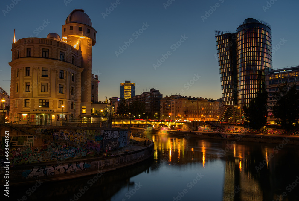 Vienna cityscape with modern Uniqa and Urania tower on the water channel at night, Austria