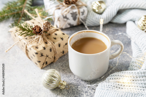 Christmas composition with cup of coffee, knitted blanket, garland and gift on a gray background. Winter, Christmas concept.