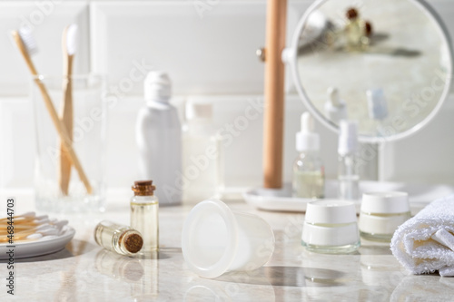 Vacuum jar for massage in the bathroom. Mirror, massage oil, towel, cream, cotton swabs in the background.