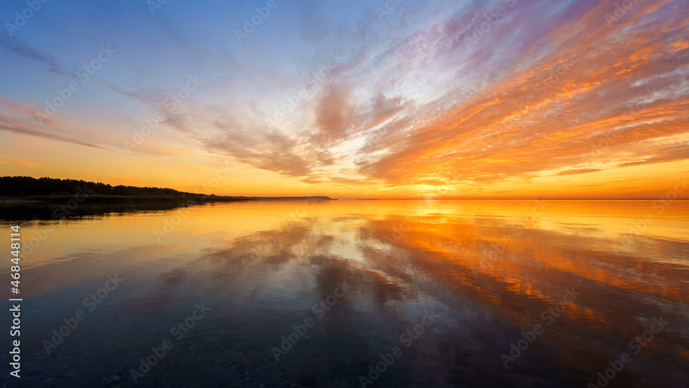 Orange sunset on a quiet lake, sunset reflected in calm water