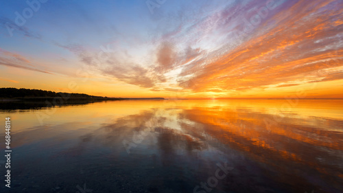 Orange sunset on a quiet lake, sunset reflected in calm water © Dmitriy Popov