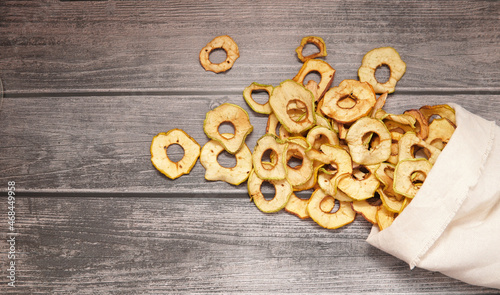dried apples are poured into rings from a bag on a wooden table.