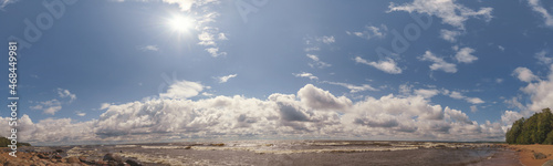 Wide angle HDR view of the sea and cloudy sky with bright summer sun