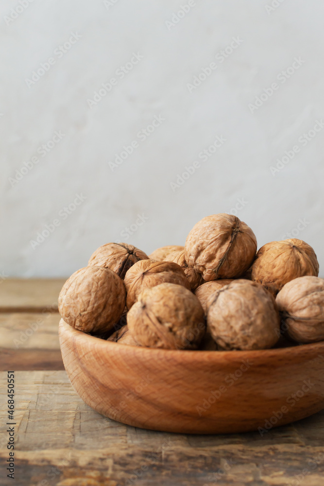 Young walnuts lie in a wooden bowl on a wooden table. Rustic style. Healthy nutrition concept. Vertical orientation. Copy space. Young walnuts lie in a wooden bowl on a wooden table. Rustic style. Healthy nutrition concept. Vertical orientation. Copy space.
