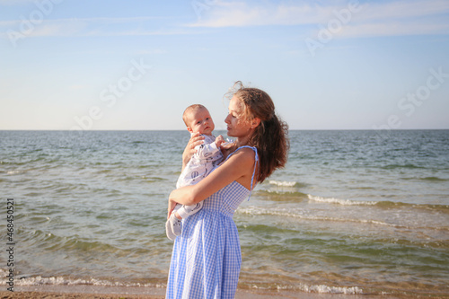 The concept of a happy harmonious family and happy motherhood outdoors. Mother hugs her baby against the background of the sea