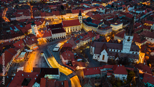 Birds eye view over historic city center of Sibiu, Romania at sunset. Drone photography from above containing the Evangelical Cathedral and Hued square, small square and the big square. © Ioan