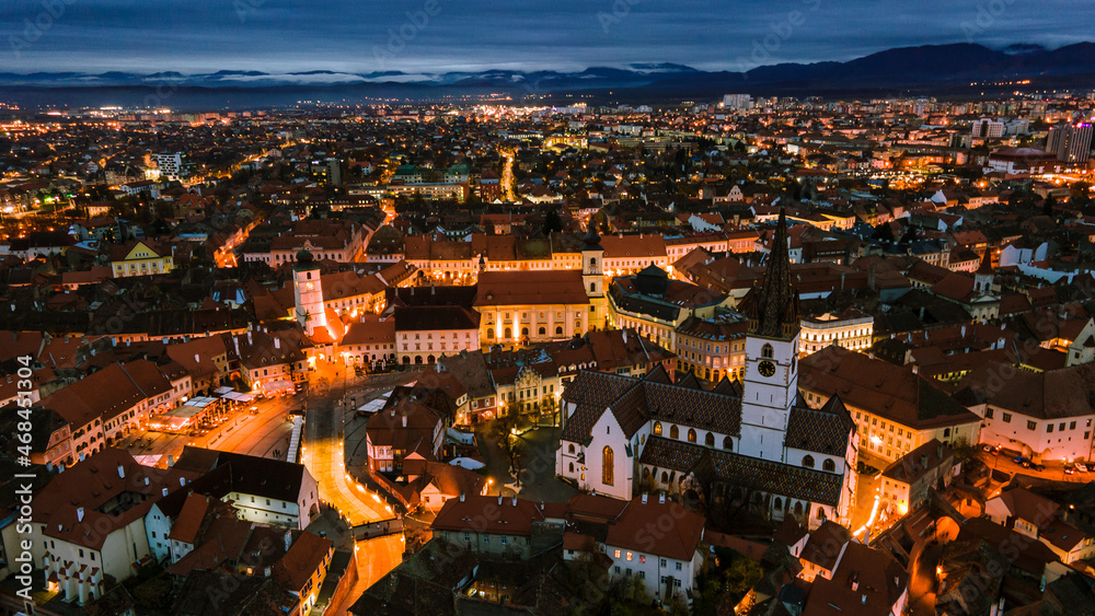 Obraz premium Aerial photography of Sibiu city center shot from a drone at sunset with city lights on. View from above Sibiu, Romania. Landscape photography taken from above Sibiu, Romania.