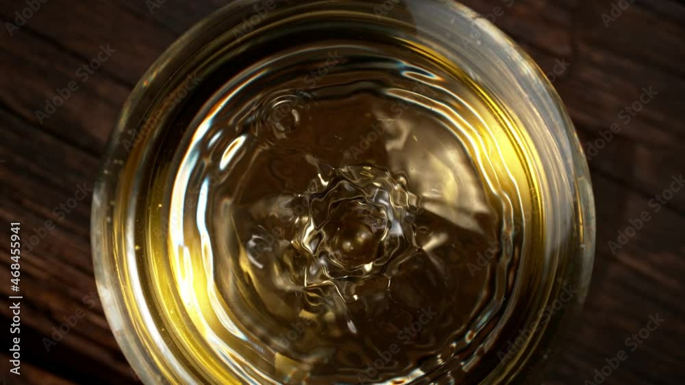 Super slow motion of dripping drop of white wine into glass. Overhead shot. Filmed on high speed cinema camera, 1000 fps Super slow motion of dripping drop of white wine into glass. Overhead shot. Filmed on high speed cinema camera, 1000 fps
