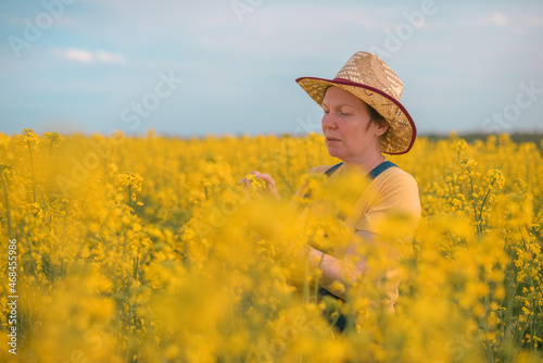 Female agronomist checking up on development of rapeseed crops in field, woman working on plantation