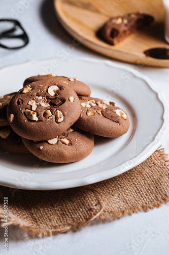 Close up of chocolate cookie with hazelnut and chocolate crumbs positioned on other cookies