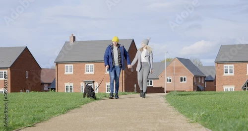 Cinematic authentic shot of young happy smiling couple walking with their dog