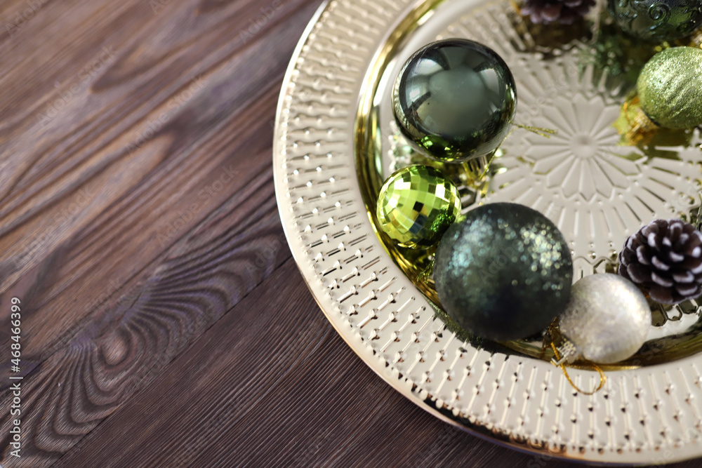 Golden round tray with Green and gold Christmas tree balls and pine cones on wooden background. Christmas background with copy space. Preparation for the New Year. High quality photo Golden round tray with Green and gold Christmas tree balls and pine cones on wooden background. Christmas background with copy space. Preparation for the New Year. High quality photo