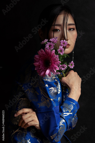 Mongolian woman with flower on black background. Beautiful young woman posing in traditional Mongolian dress.