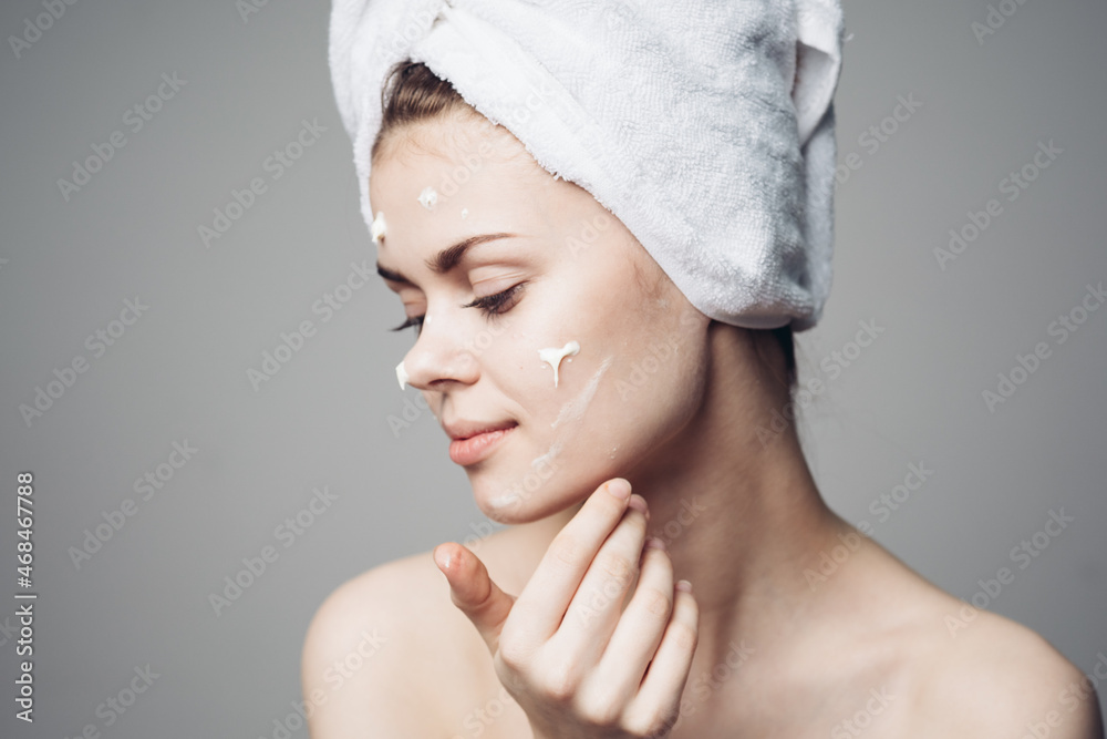 woman with bare shoulders towel on head face cream skin care