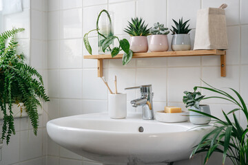 Modern white bathroom with bamboo shelf and many green plants. Home comfort zone. Wellness and yero waste