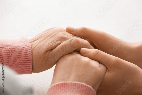 Young woman holding hands of grandmother, closeup